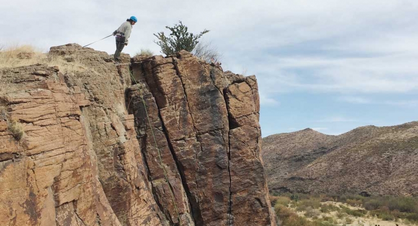 a person looks over a rock ledge while on a rock climbing course with outward bound